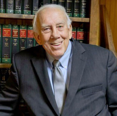 Headshot of Jim Kitchens, Esq., a smiling elderly man with gray hair in a dark suit.